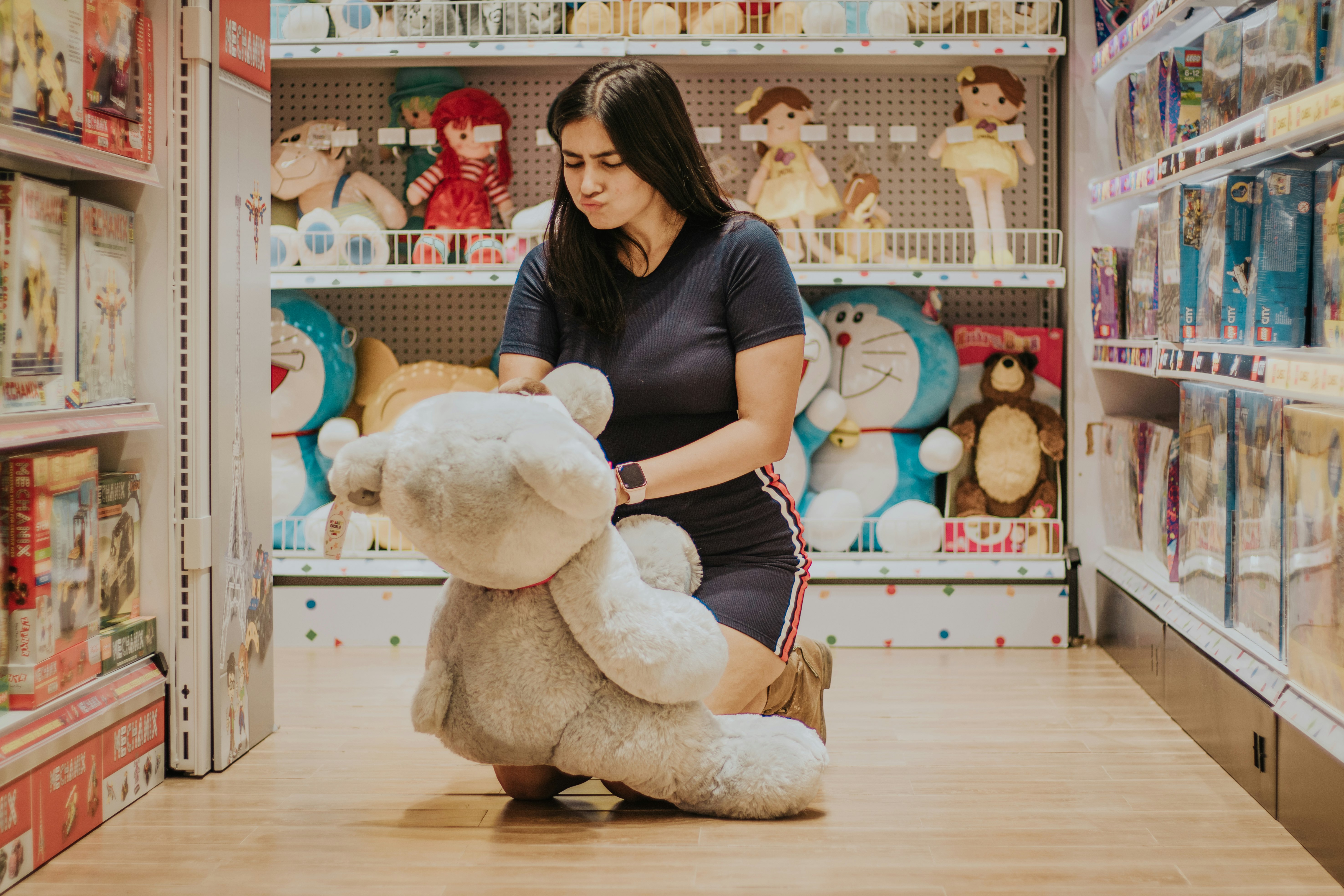 woman in black t-shirt holding white bear plush toy